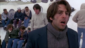 Movie still from “Alive” (1993), directed by Frank Marshall – A group of people sitting in a room with a man in a suit; Close Up shot, Low angle
