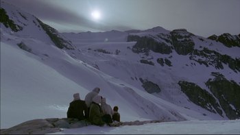 Movie still from “Alive” (1993), directed by Frank Marshall – A group of people sitting on top of a snow covered slope; Extreme Wide shot, Low angle