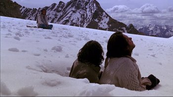 Movie still from “Alive” (1993), directed by Frank Marshall – Two people sitting in the snow on top of a mountain; Wide shot, High angle