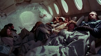 Movie still from “Alive” (1993), directed by Frank Marshall – Two men laying in a plane sleeping on a bed; Wide shot, Overhead angle