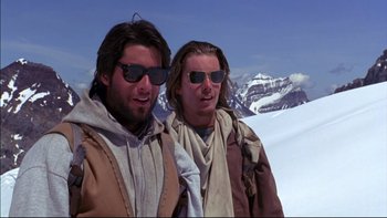 Movie still from “Alive” (1993), directed by Frank Marshall – Two men standing next to each other on top of a mountain; Medium shot, Low angle