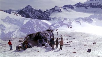 Movie still from “Alive” (1993), directed by Frank Marshall – A group of people standing around a plane wreckage in the snow; Extreme Wide shot, High angle