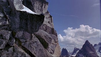 Movie still from “Alive” (1993), directed by Frank Marshall – A view of a rocky mountain side with a sky background; Extreme Wide shot, Low angle