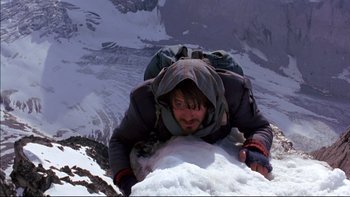 Movie still from “Alive” (1993), directed by Frank Marshall – A man is climbing up the side of a snow covered mountain; Wide shot, Low angle
