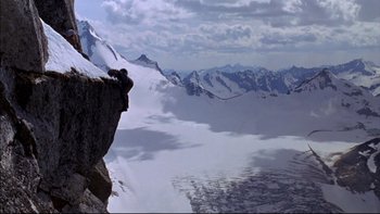 Movie still from “Alive” (1993), directed by Frank Marshall – A person standing on top of a cliff in front of a body of water; Extreme Wide shot, High angle