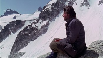 Movie still from “Alive” (1993), directed by Frank Marshall – A man sitting on the side of a snow covered mountain; Wide shot, Low angle