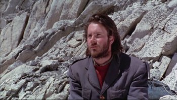 Movie still from “Alive” (1993), directed by Frank Marshall – A man sitting on top of a rock face; Close Up shot, Low angle