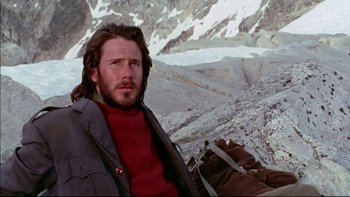Movie still from “Alive” (1993), directed by Frank Marshall – A man in a red sweater is sitting in front of a snowy mountain; Medium shot, Low angle