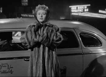 Movie still from “All About Eve” (1950), directed by Joseph L. Mankiewicz – A black and white photo of a woman in a fur coat; Medium shot, Low angle