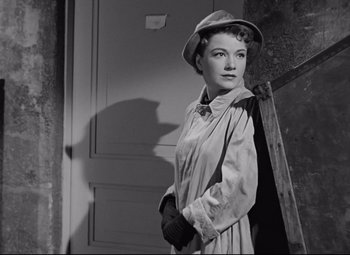 Movie still from “All About Eve” (1950), directed by Joseph L. Mankiewicz – A black and white photo of a woman in a trench coat and hat; Medium shot, Low angle