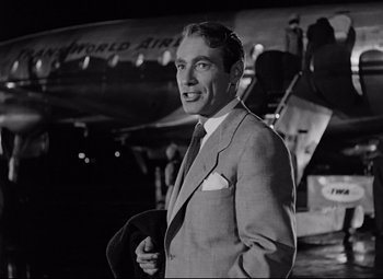 Movie still from “All About Eve” (1950), directed by Joseph L. Mankiewicz – A man in a suit and tie standing next to an airplane; Close Up shot, Low angle