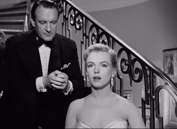 Movie still from “All About Eve” (1950), directed by Joseph L. Mankiewicz – A man and a woman standing next to each other in front of a staircase; Medium shot, Low angle