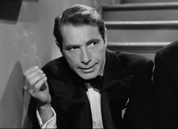 Movie still from “All About Eve” (1950), directed by Joseph L. Mankiewicz – A black and white photo of a man smoking a cigarette; Close Up shot, Over the shoulder angle