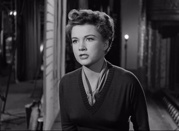 Movie still from “All About Eve” (1950), directed by Joseph L. Mankiewicz – A black and white photo of a woman in a sweater; Close Up shot, Low angle