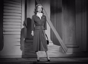 Movie still from “All About Eve” (1950), directed by Joseph L. Mankiewicz – A black and white photo of a woman in a dress; Medium shot, Low angle