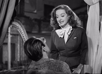 Movie still from “All About Eve” (1950), directed by Joseph L. Mankiewicz – An old photo of a woman talking to a young man; Medium shot, Low angle