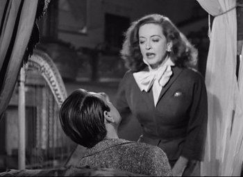 Movie still from “All About Eve” (1950), directed by Joseph L. Mankiewicz – A woman talking to another woman in a room; Medium shot, Low angle