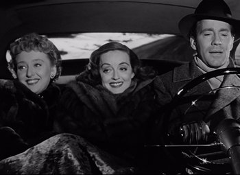 Movie still from “All About Eve” (1950), directed by Joseph L. Mankiewicz – A group of people sitting in the back seat of a car; Medium shot, Low angle