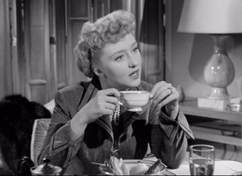 Movie still from “All About Eve” (1950), directed by Joseph L. Mankiewicz – A woman sitting at a table with a cup of tea; Close Up shot, Low angle