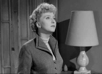 Movie still from “All About Eve” (1950), directed by Joseph L. Mankiewicz – An older woman standing in front of a table lamp; Close Up shot, Low angle