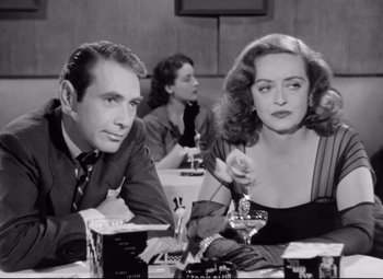Movie still from “All About Eve” (1950), directed by Joseph L. Mankiewicz – A man and a woman sitting at a dinner table; Close Up shot, Low angle