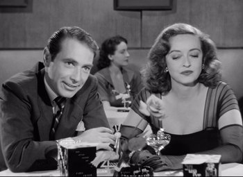Movie still from “All About Eve” (1950), directed by Joseph L. Mankiewicz – A man and a woman sitting at a table in a restaurant; Medium shot, High angle