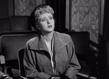 Movie still from “All About Eve” (1950), directed by Joseph L. Mankiewicz – An old black and white photo of a woman sitting at a desk; Medium shot, Low angle