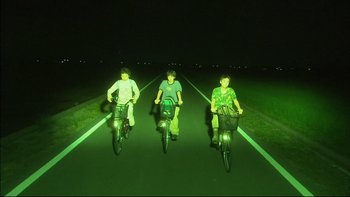 Movie still from “All About Lily Chou-Chou” (2001), directed by Shunji Iwai – Three young men riding bikes down a street at night; Wide shot, Low angle