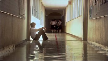 Movie still from “All About Lily Chou-Chou” (2001), directed by Shunji Iwai – A man sitting on the floor of a school hallway; Extreme Wide shot, High angle