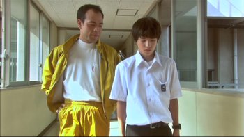 Movie still from “All About Lily Chou-Chou” (2001), directed by Shunji Iwai – A man and a young boy standing next to each other; Medium shot, Low angle