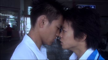 Movie still from “All About Lily Chou-Chou” (2001), directed by Shunji Iwai – Two young asian men face to face in a courtyard; Close Up shot, Low angle