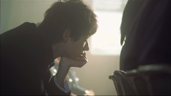 Movie still from “All About Lily Chou-Chou” (2001), directed by Shunji Iwai – A young man looking at something on a table; Close Up shot, Low angle