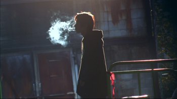 Movie still from “All About Lily Chou-Chou” (2001), directed by Shunji Iwai – A person is smoking a cigarette in the dark; Medium shot, Low angle