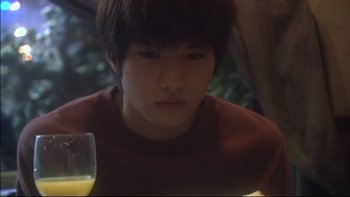 Movie still from “All About Lily Chou-Chou” (2001), directed by Shunji Iwai – A young man sitting in front of a glass of orange juice; Close Up shot, Low angle