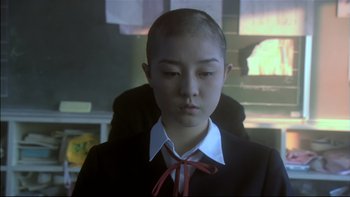 Movie still from “All About Lily Chou-Chou” (2001), directed by Shunji Iwai – A young boy with a bow tie sitting in a chair; Close Up shot, Low angle