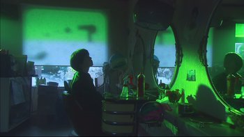 Movie still from “All About Lily Chou-Chou” (2001), directed by Shunji Iwai – A boy sitting in front of a mirror in a room; Wide shot, Over the shoulder angle