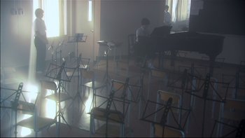Movie still from “All About Lily Chou-Chou” (2001), directed by Shunji Iwai – A room filled with chairs and a piano; Extreme Wide shot, High angle
