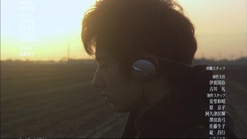 Movie still from “All About Lily Chou-Chou” (2001), directed by Shunji Iwai – A person with headphones in a field at sunset; Close Up shot, Low angle