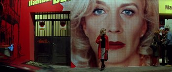 Movie still from “All About My Mother” (1999), directed by Pedro Almodóvar – A woman walking down the street in front of an advertisement; Wide shot, Low angle