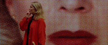 Movie still from “All About My Mother” (1999), directed by Pedro Almodóvar – A woman wearing a red shirt is standing in front of a wall with an image of a woman's face on it; Extreme Close Up shot, Low angle