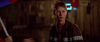 Movie still from “All About My Mother” (1999), directed by Pedro Almodóvar – A young man standing in the pouring rain; Close Up shot, Over the shoulder angle