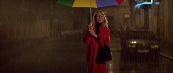 Movie still from “All About My Mother” (1999), directed by Pedro Almodóvar – A woman in a red coat holding an open umbrella; Medium shot, Low angle