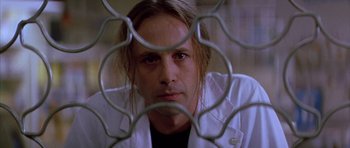 Movie still from “All About My Mother” (1999), directed by Pedro Almodóvar – A man in a white lab coat behind a metal fence; Close Up shot, Low angle