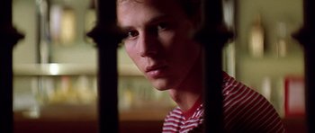 Movie still from “All About My Mother” (1999), directed by Pedro Almodóvar – A young man is looking through bars of a window; Close Up shot, Low angle