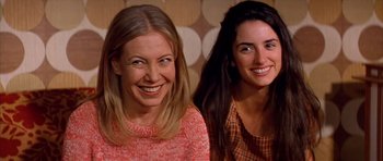 Movie still from “All About My Mother” (1999), directed by Pedro Almodóvar – Two women smile for the camera while posing for a picture; Close Up shot, Low angle