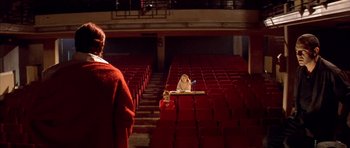 Movie still from “All About My Mother” (1999), directed by Pedro Almodóvar – Two people are sitting in a theater while one person takes a picture; Wide shot, Low angle