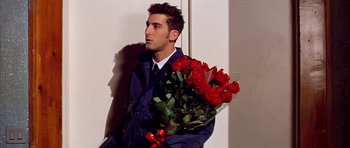 Movie still from “All About My Mother” (1999), directed by Pedro Almodóvar – A man holding a bouquet of red roses; Medium shot, High angle