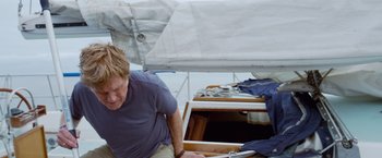 Movie still from “All Is Lost” (2013), directed by J.C. Chandor – A man standing next to a boat on the water; Medium shot, Low angle