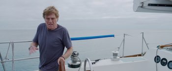 Movie still from “All Is Lost” (2013), directed by J.C. Chandor – A man standing on the deck of a sailboat in the ocean; Medium shot, Low angle