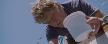 Movie still from “All Is Lost” (2013), directed by J.C. Chandor – A man holding onto a white bucket on the side of a boat; Close Up shot, Low angle